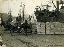 Málaga, muelle de carga en el Puerto con las mercancías y los carros de mulas junto a los barcos. Foto Greco.