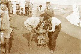 Málaga, en la playa unos niños muestran una medusa, detrás nos pescadores con un "copo". Fotógrafo desconocido.