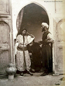 Tánger (Marruecos), retrato de una pareja con vestidos tradicionales marroquíes, él porta una gnawa. James Mann